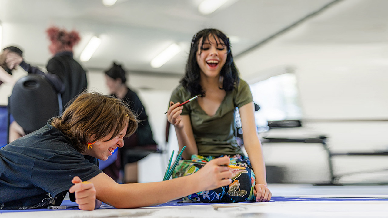 Two young people painting an artwork and enjoying themselves.