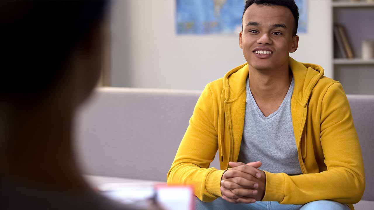 An young man is talking with a counsellor.